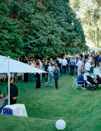 Festa di compleanno a Villa Puccini con panoramica sul prato e gli invitati sparsi, con in primo piano un gazebo