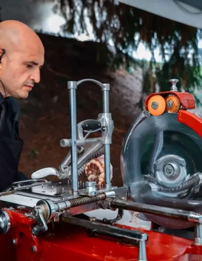 Inserviente in abito scuro con auricolare che taglia i salumi per una festa privata in Villa Puccini