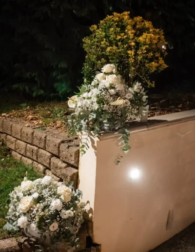 Particolare di un muretto addobbato con rose bianche