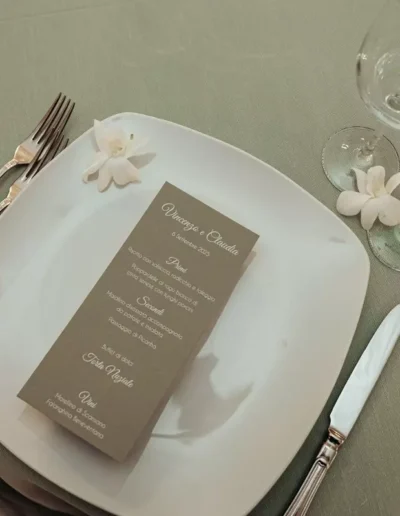 Particolare di un piatto di un matrimonio con la carta del menu appoggiata sopra