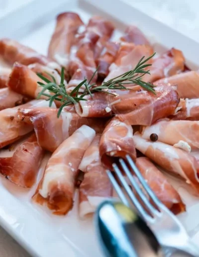 Piatto di prosciutto crudo aromatizzato, in un piatto bianco con tovaglia bianca