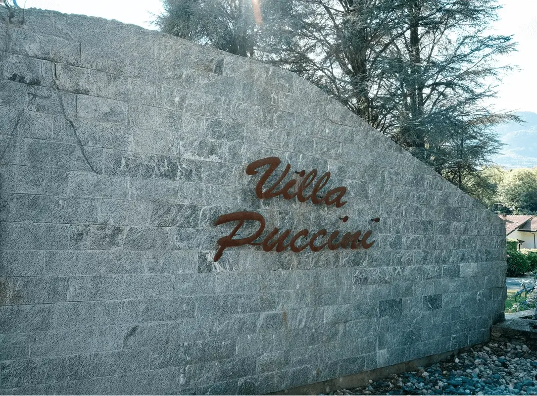chi-siamo-villa-puccini Muro con la scritta Villa Puccini in bronzo